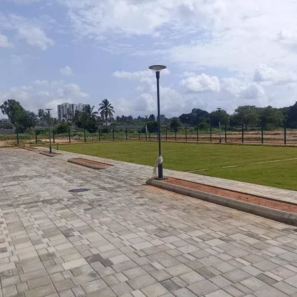 Paved plot frontages and open ground at the Adarsh Springfield site with the city skyline beyond, photograph
